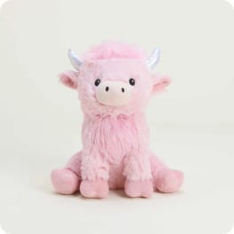 Pink plush cow toy with silver horns sitting on a plain background