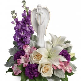 White angel figurine surrounded by purple, pink, and white flowers