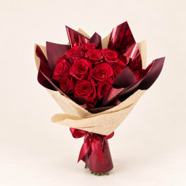 Bouquet of red roses wrapped in burgundy and cream paper with a ribbon