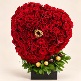 Heart-shaped red rose arrangement with chocolates in a black box