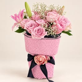 Pink rose bouquet in a textured pink hatbox with a black ribbon