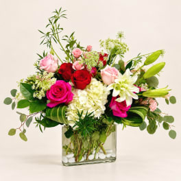Mixed bouquet of roses, hydrangea, and lilies in a glass vase