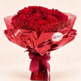 Bouquet of red roses wrapped in shiny red paper with a ribbon
