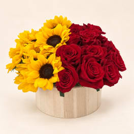 Red roses and yellow sunflowers in a round wooden box