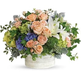 Peach roses and white lilies in a white round container