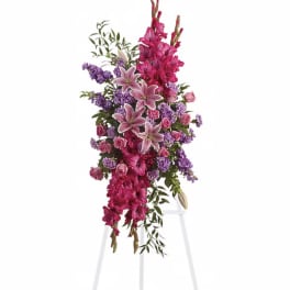 Tall pink and purple floral arrangement on a white stand