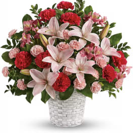 Pink lilies and red carnations arranged in a white woven basket
