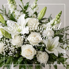 White lilies and roses in a sympathy arrangement with green foliage