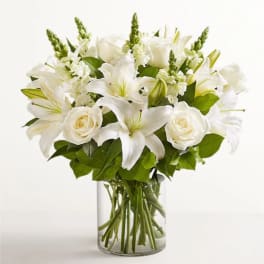 White lilies and roses arranged in a clear glass vase