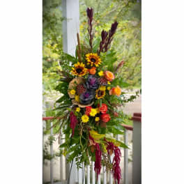 Tall mixed floral arrangement with sunflowers, roses, and purple accents