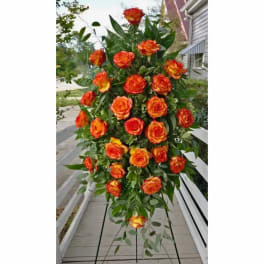 Tall standing spray of orange and yellow roses with greenery