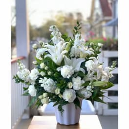 White lilies and carnations arranged in a white vase