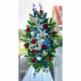 Tall floral arrangement with white lilies, red roses, and blue accents