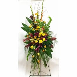Tall standing floral spray with yellow, purple, and red blooms on a metal easel