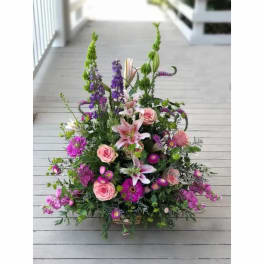 Large mixed bouquet with pink roses, lilies, and purple flowers in a basket