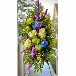 Tall colorful floral arrangement with blue, green, purple, and yellow blooms