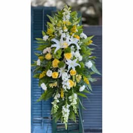 Tall floral spray with white lilies, yellow roses, and green accents