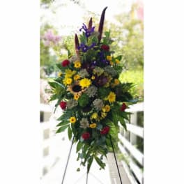 Tall standing floral spray with sunflowers, red carnations, and purple irises