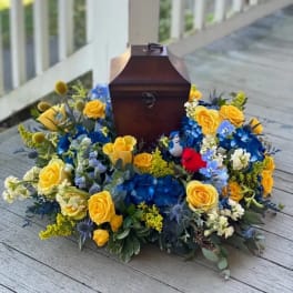 Yellow roses and blue flowers arranged around a wooden keepsake box