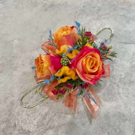 Small colorful floral corsage with roses and ribbon on a gray surface