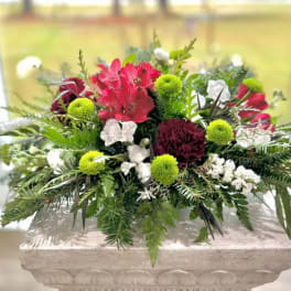 Mixed red, white, and green floral arrangement in a low stone container