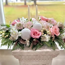 Pink roses and white flowers arranged with candles in a pedestal vase