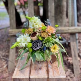 Compact floral arrangement with white, peach, and yellow blooms in a low container