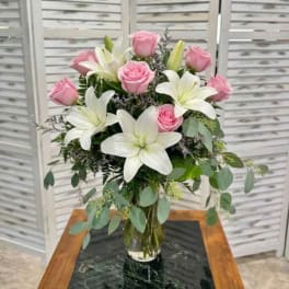 Pink roses and white lilies arranged in a clear glass vase