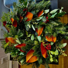 Holiday wreath with evergreen branches, red berries, and orange leaves