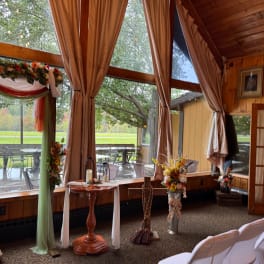 Wedding ceremony setup with floral arrangements and draped fabric in a wood-paneled room