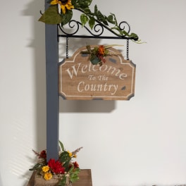 Decorative wooden welcome sign with small floral accents