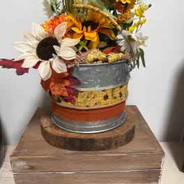 Fall floral arrangement in a galvanized bucket with sunflowers and daisies