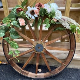 Floral arrangement on a wooden wagon wheel with roses and daisies