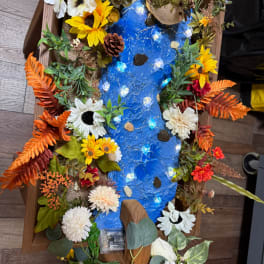 Decorative floral display with a blue river-like center and mixed flowers around it