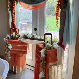 Decorated window display with white flowers, orange draping, and lanterns