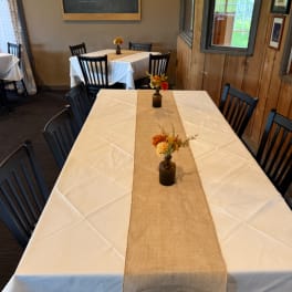 Small floral centerpieces in brown bottles on a table runner