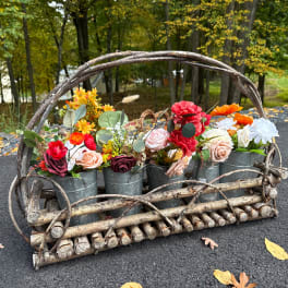Colorful flower arrangement in metal buckets inside a rustic wooden basket