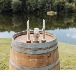 Three white candles on a wooden barrel by the water