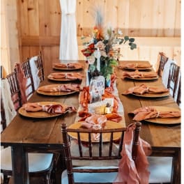 Floral centerpiece on a long table set with copper plates and napkins