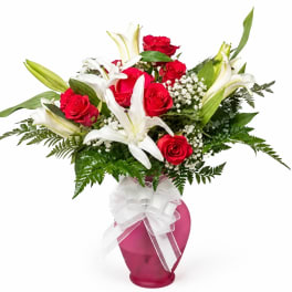 Red roses and white lilies in a pink vase with a white bow