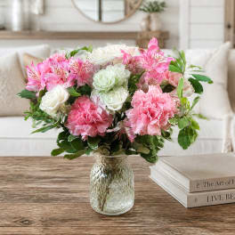 Pink and white flower arrangement in a clear glass vase on a table