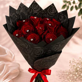 Bouquet of red roses wrapped in black paper with a red ribbon