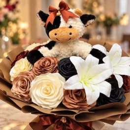 Plush cow sitting in a bouquet of roses and white lilies
