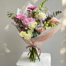 Pink and cream bouquet with roses, gerberas, and carnations wrapped in blush paper