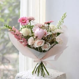 Pink and white mixed bouquet wrapped in pale paper with a ribbon