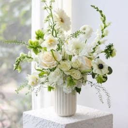 White floral arrangement in a ribbed vase with airy green accents