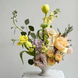 Pastel floral arrangement in a white pedestal vase