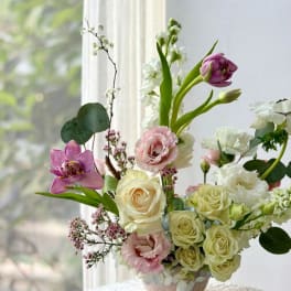 Bouquet of pink and white flowers in a vase by a window