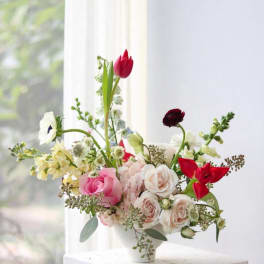 Mixed bouquet of pink, white, and red flowers in a white vase