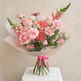 Pink mixed bouquet wrapped in pale paper with a ribbon